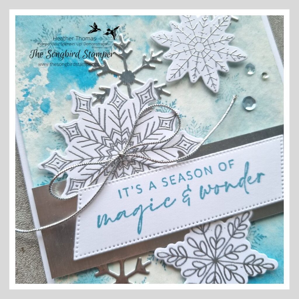 A handmade Christmas card in blue with snowflakes showing how to create an ink smooshing background