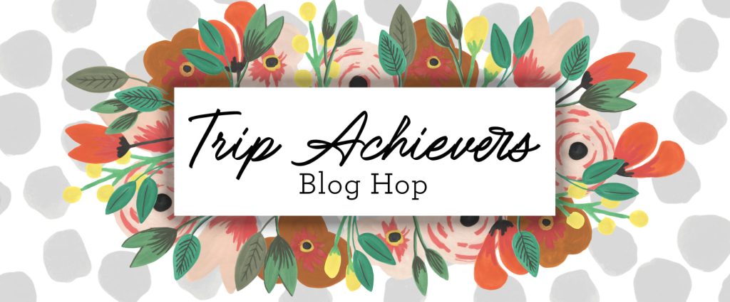 Trip Achievers Blog Hop Banner with a floral arrangement around the words Trip Achievers Blog Hop