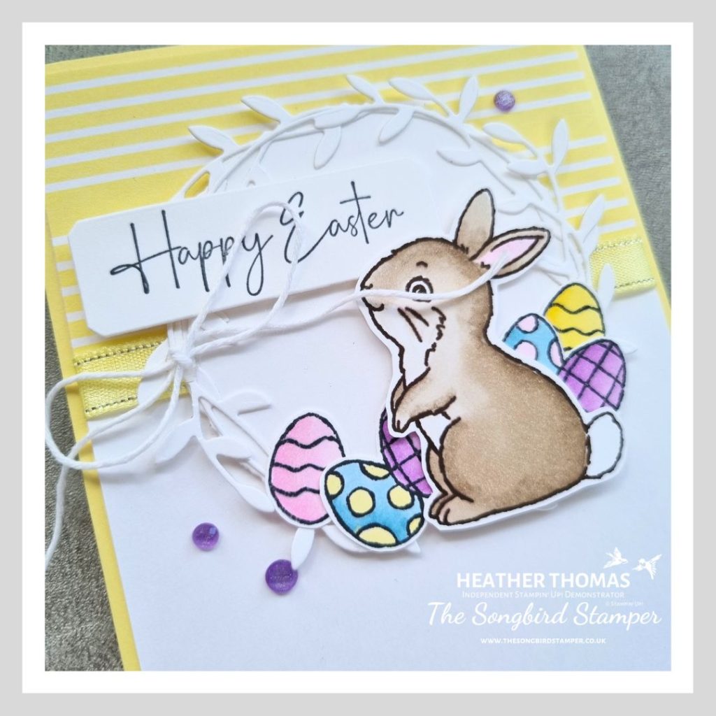 A close up of an easy Easter card in yellow and white with a hand coloured rabbit and some easter eggs, with the words Happy Easter