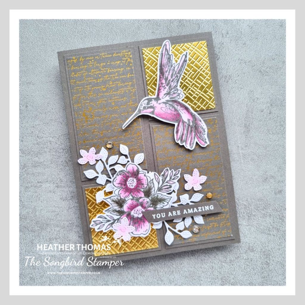 A gold and grey panelled handmade card with a pop of color in pink, with a hummingbird and a floral and leaf image.