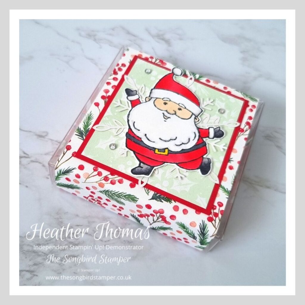 A handmade stocking filler filled with Lindt chocolate balls and decorated with a jolly Santa and red and green papers.