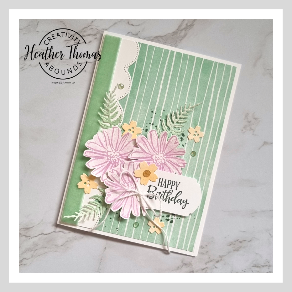A fun and fresh birthday card in green, purple and orange with flowers and leaves and ribbon.