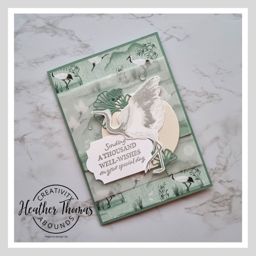 A handmade card in green and grey with a crane on, showing how to make a vellum wrap