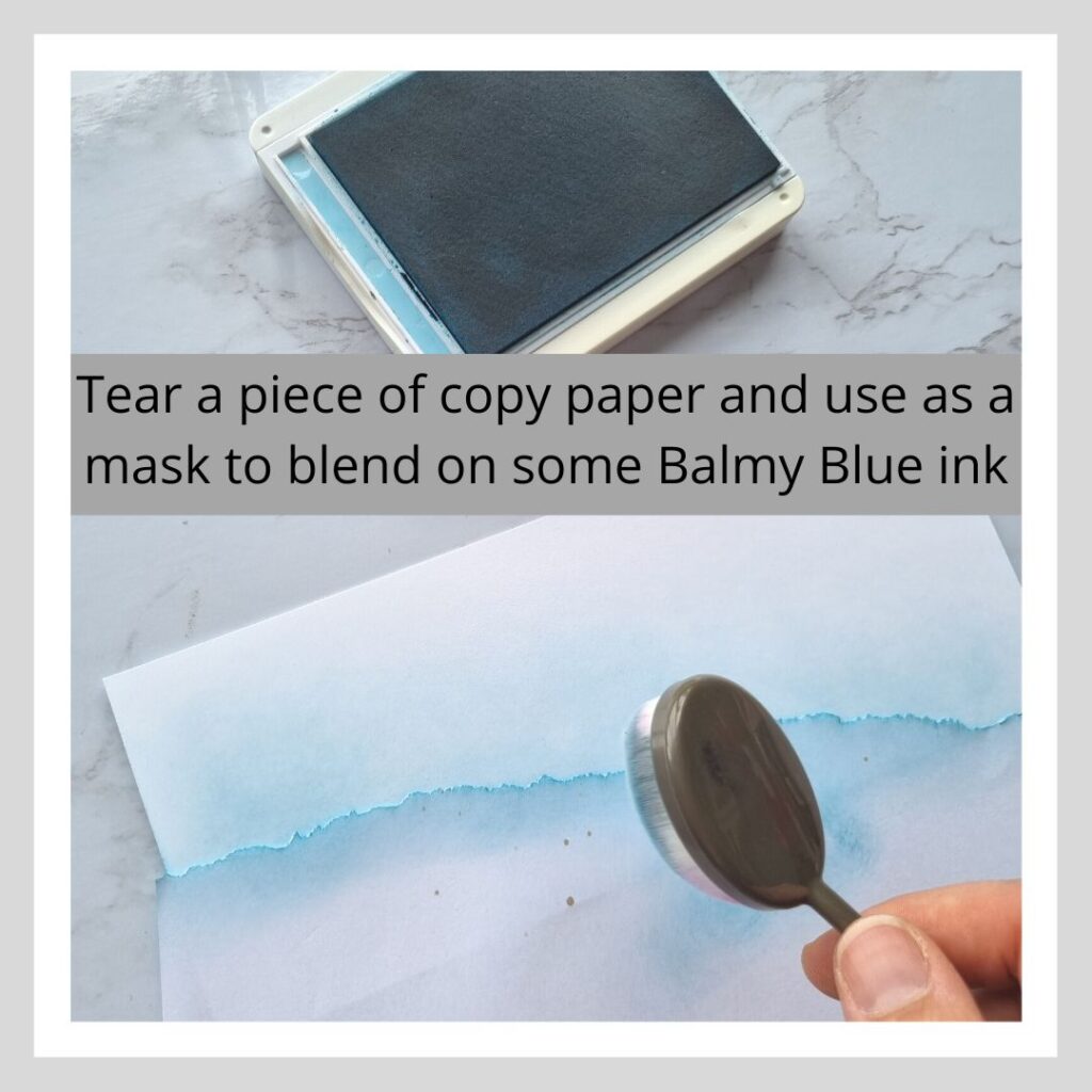 Step one of three step by step instructions on how to create a beach scene. Text says "tear a piece of copy paper and use it as a mask to blend on some balmy blue ink"