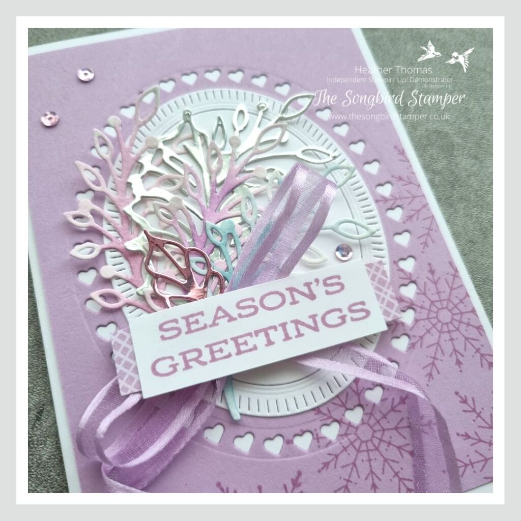 A very purple Christmas card with the words Season's Greetings and die cuts in purple, blue and silver, and purple ribbon