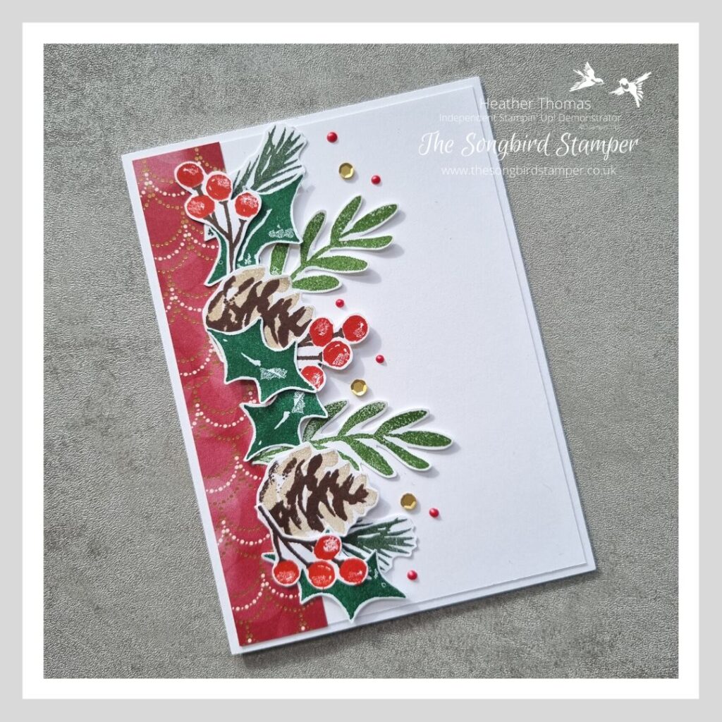 A Christmas card in red, green and gold, with pine cones, leaves and berries.