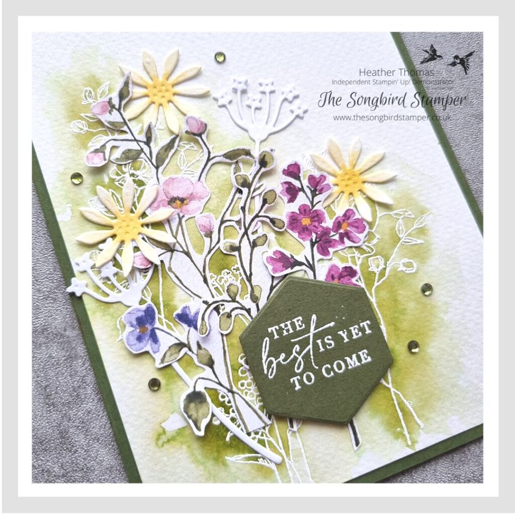 A handmade card in greens, pinks and yellows, with a spray of flowers using the emboss resist technique