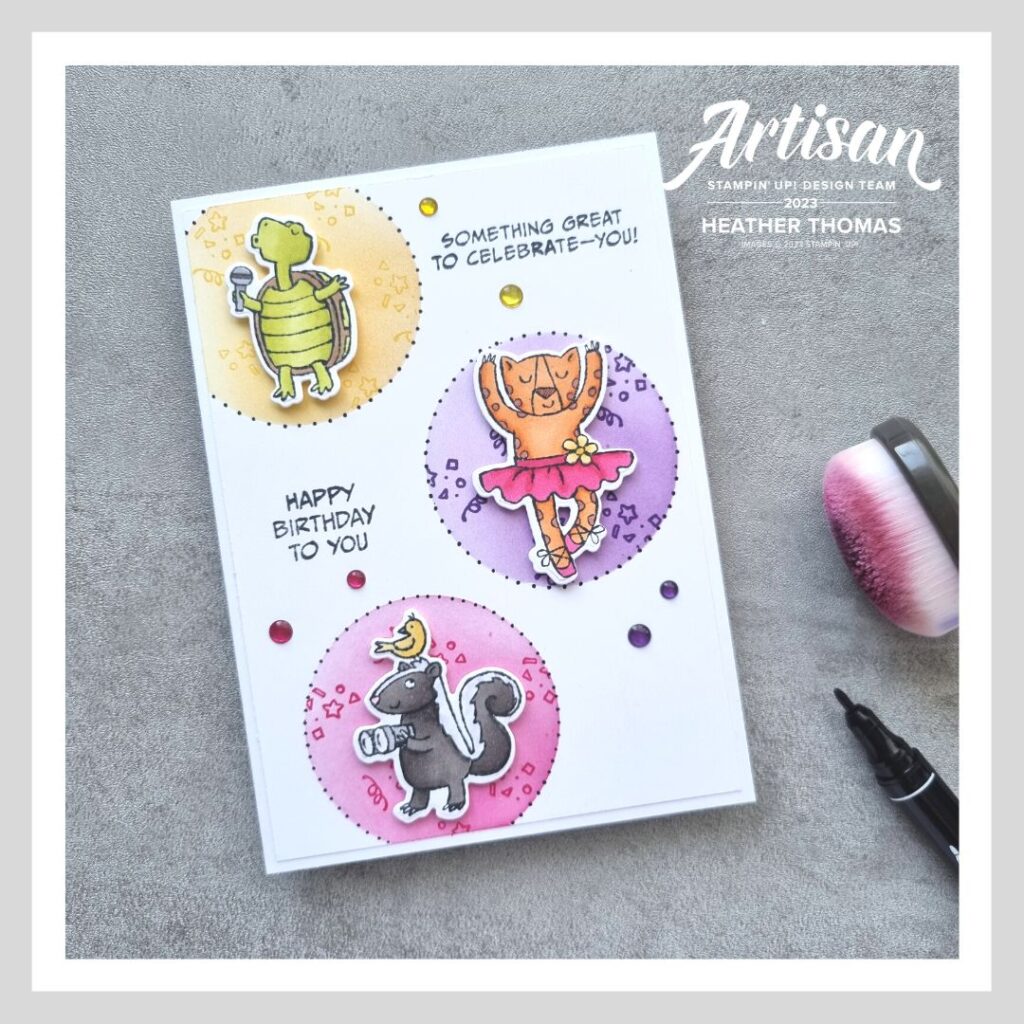 A handmade card with circles of bright colours and three cute animals coloured in with alcohol markers.
