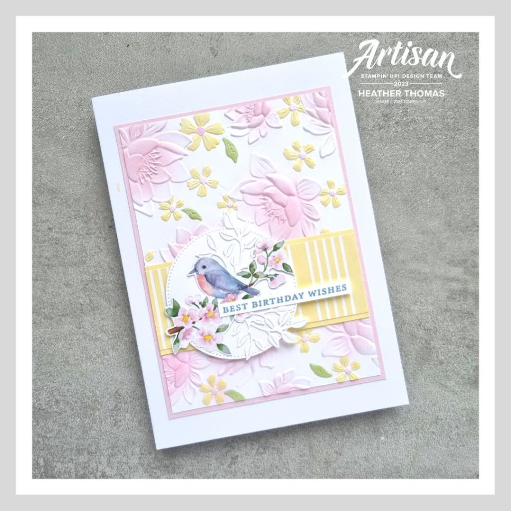 A Spring inspired birthday card with pinks, yellows, blues and greens, and embossed floral background and a cut bird nestled among some leaves.
