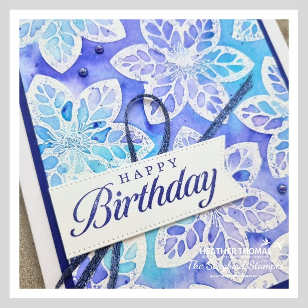 A close up of a handmade card using the emboss resist technique and watercolour, in blues and purples.