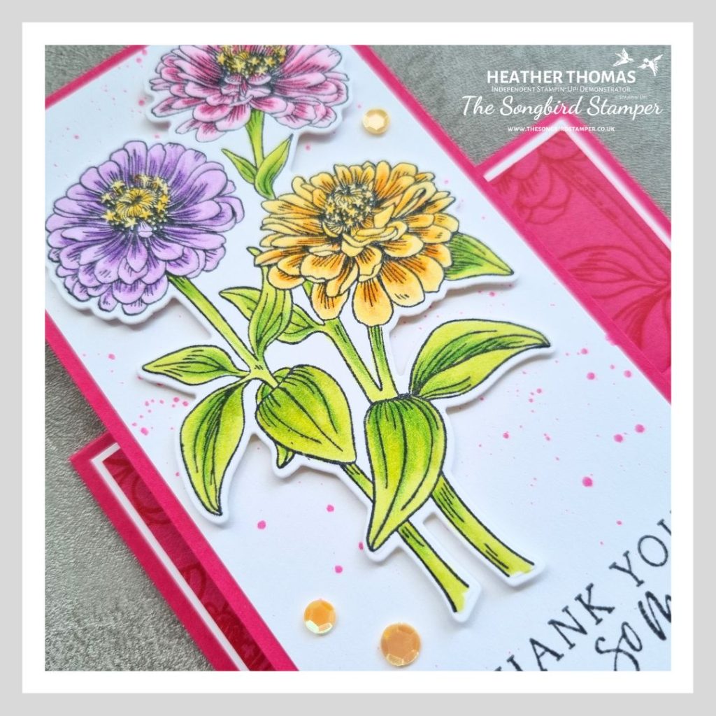 A close up of a faux stepper card in pink, with flowering zinnias coloured in with green, yellow, purple and pink